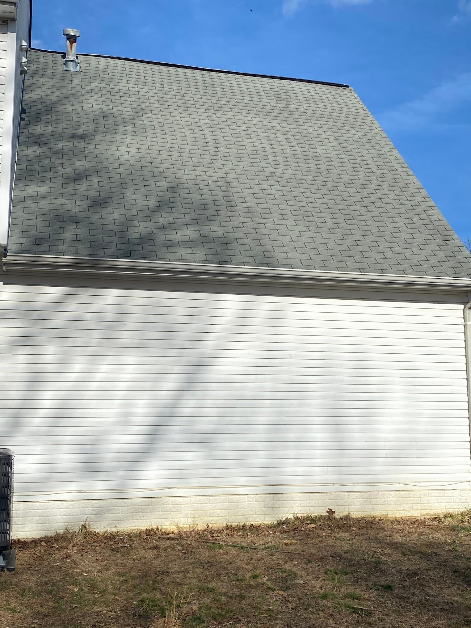 A white house with a gray roof and a blue sky in the background.