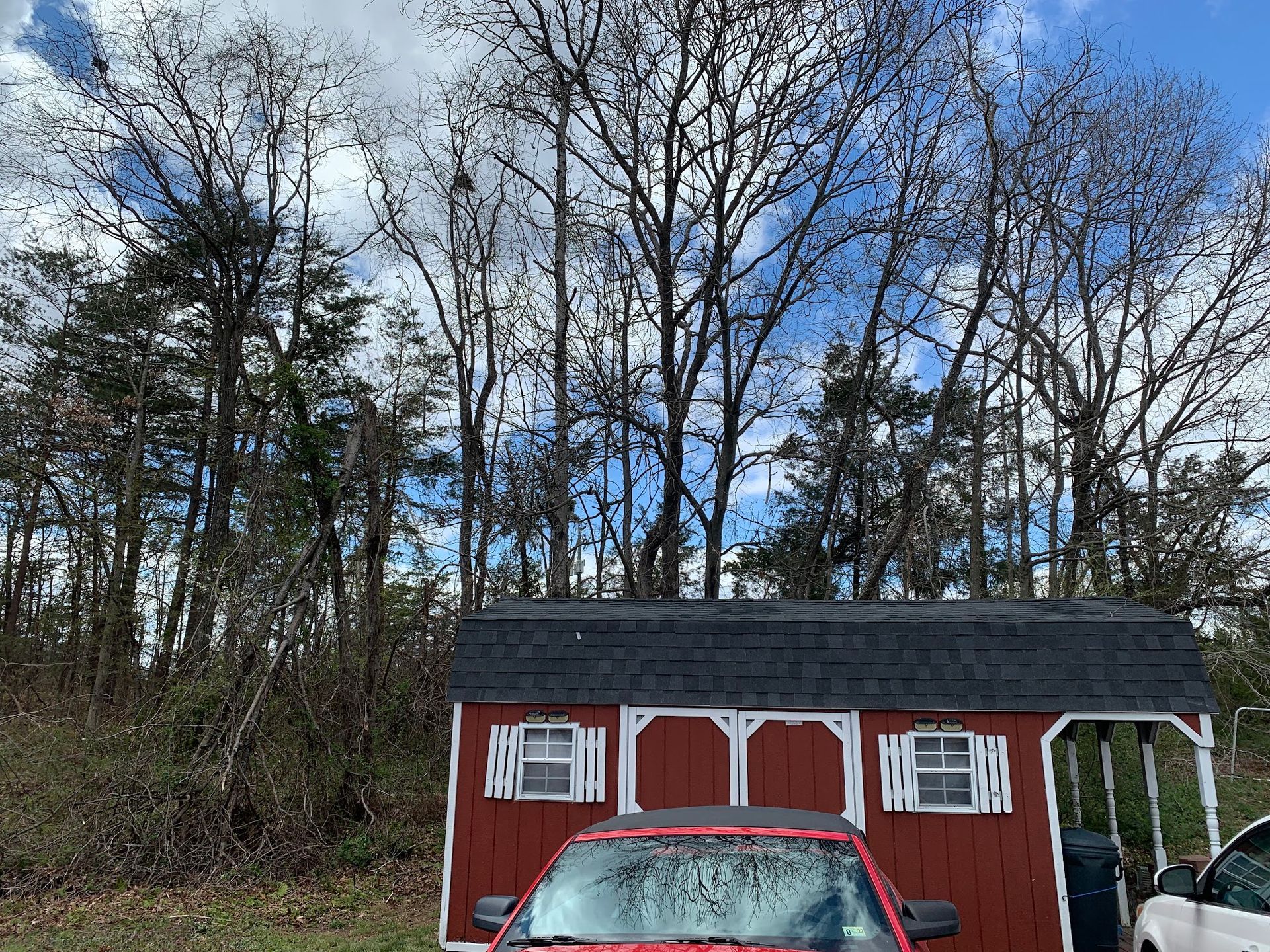A red truck is parked in front of a red barn.