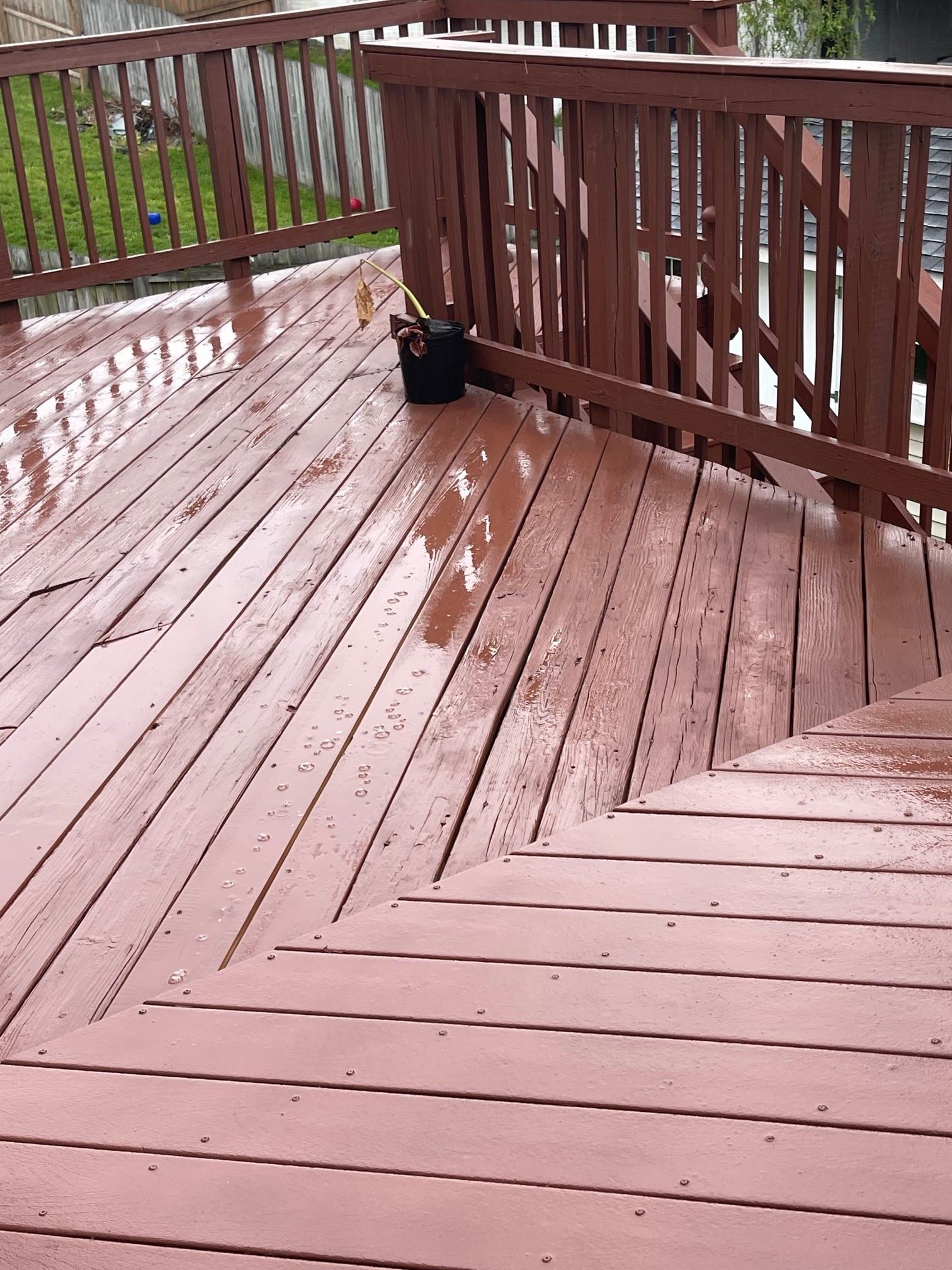 A wooden deck with a railing and a potted plant on it.