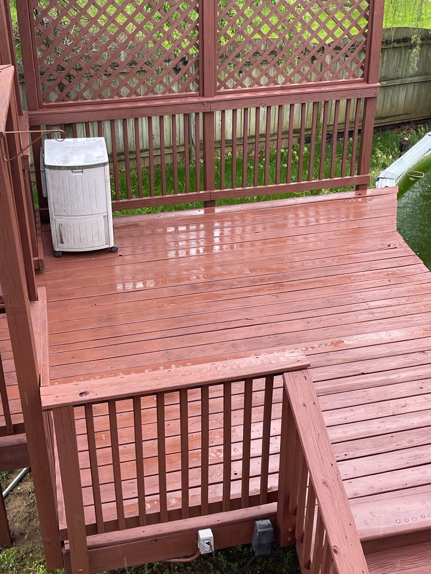 A wooden deck with stairs and a trash can on it.