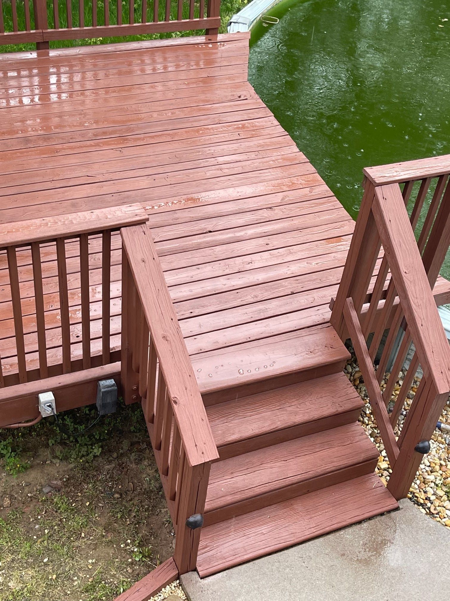A wooden deck with stairs leading to a pond.