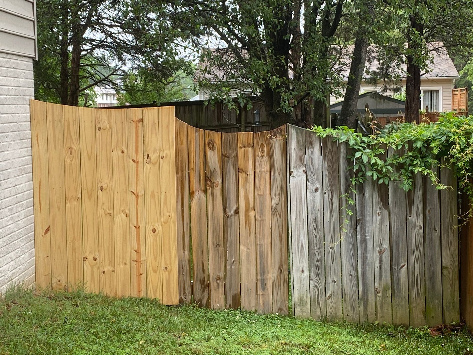 A before and after picture of a wooden fence in a backyard.