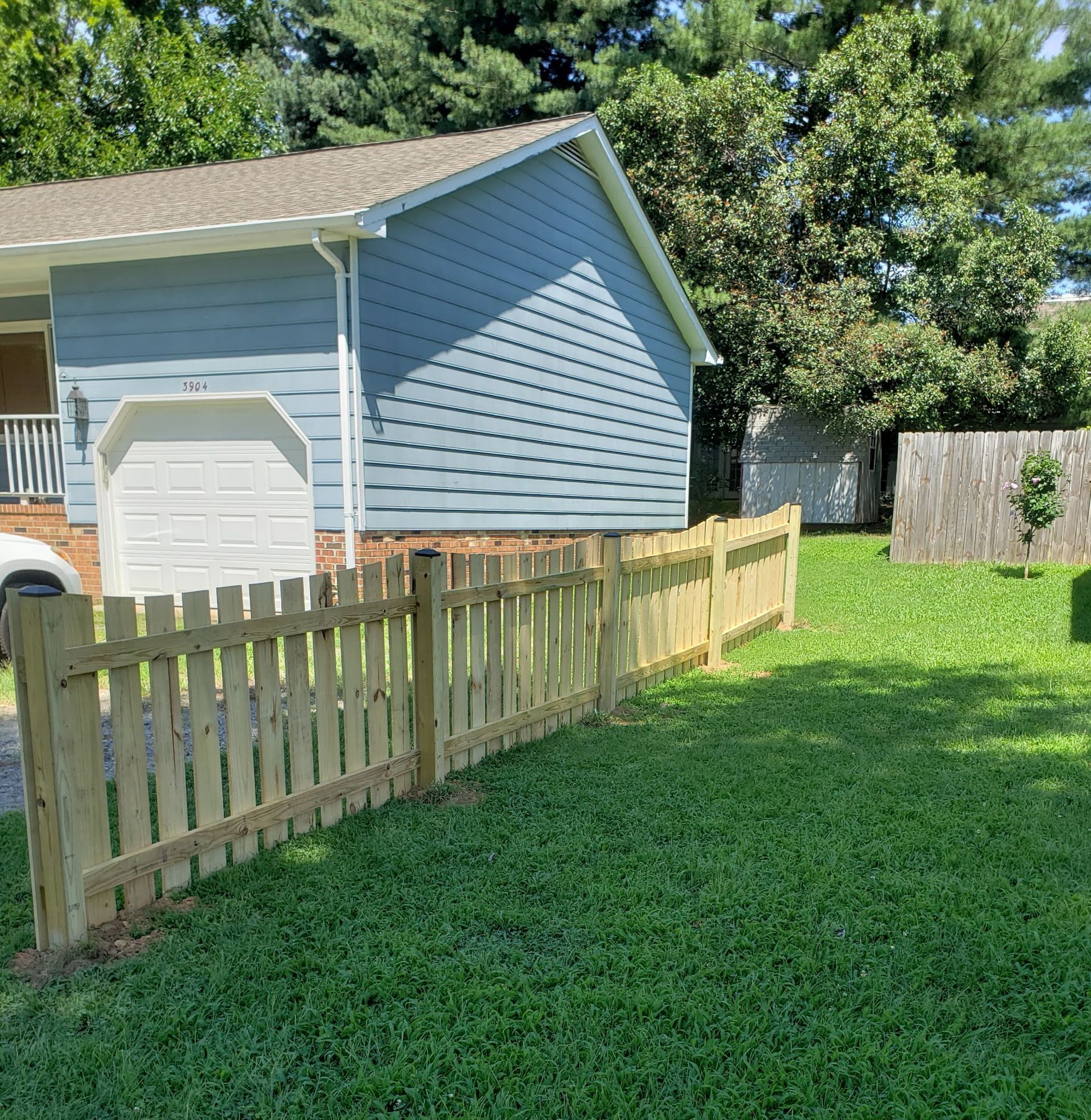 A blue house with a wooden fence in front of it.