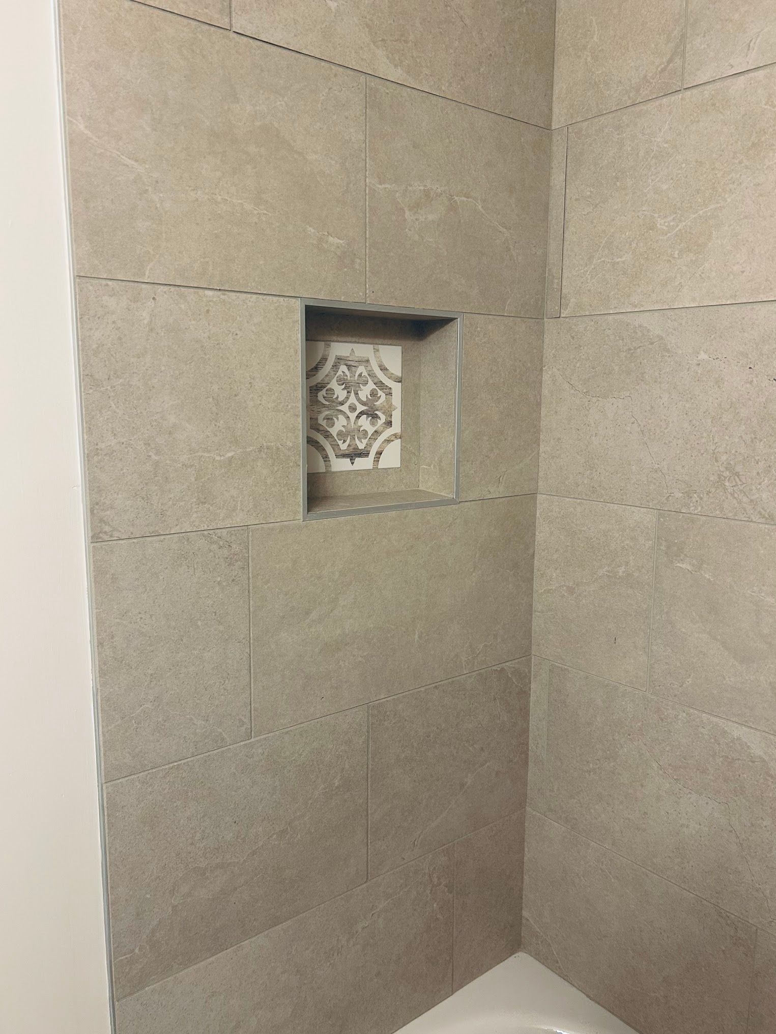 A shower stall with a tiled niche in the wall.