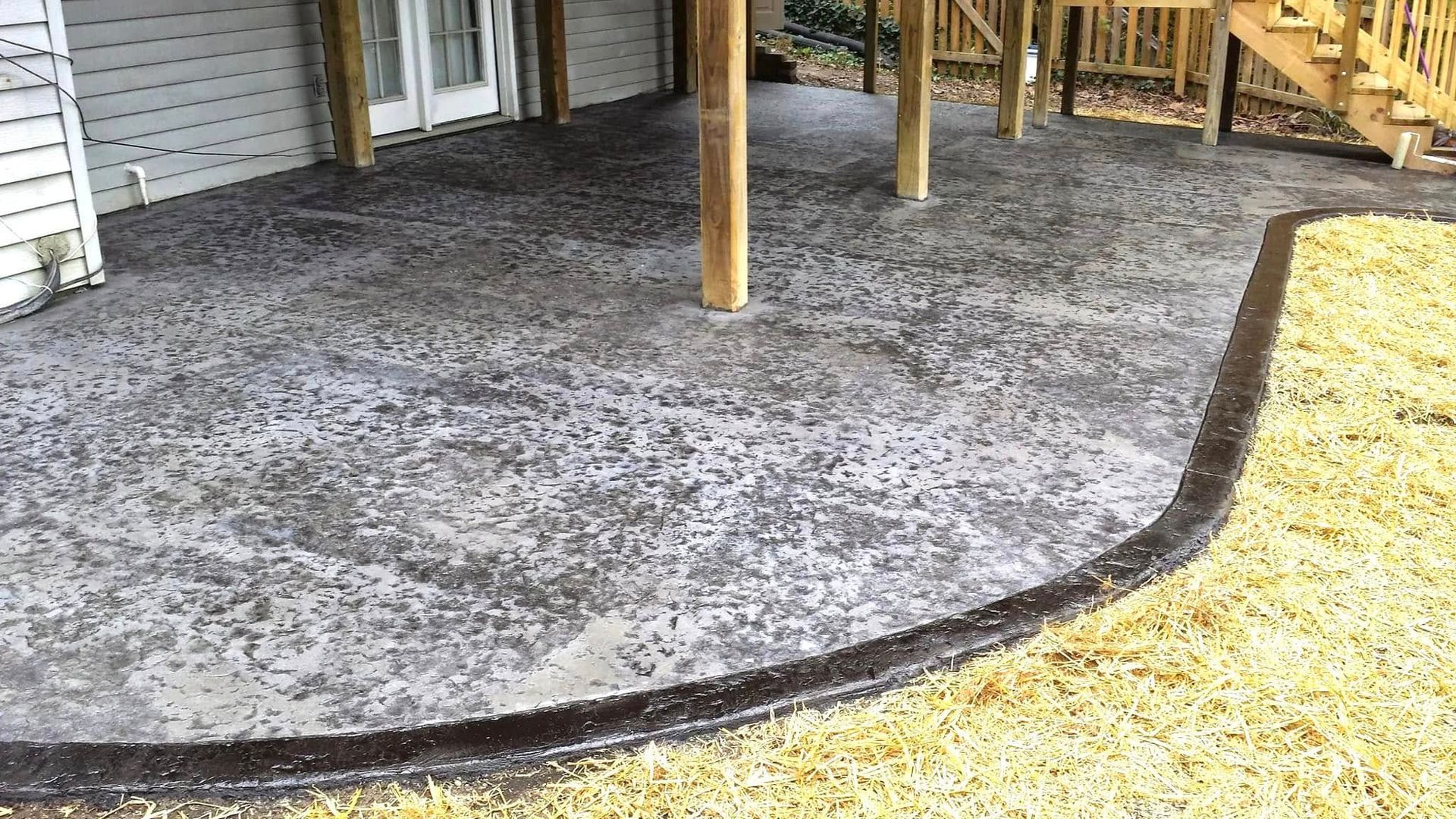 A concrete patio with a wooden deck underneath it.