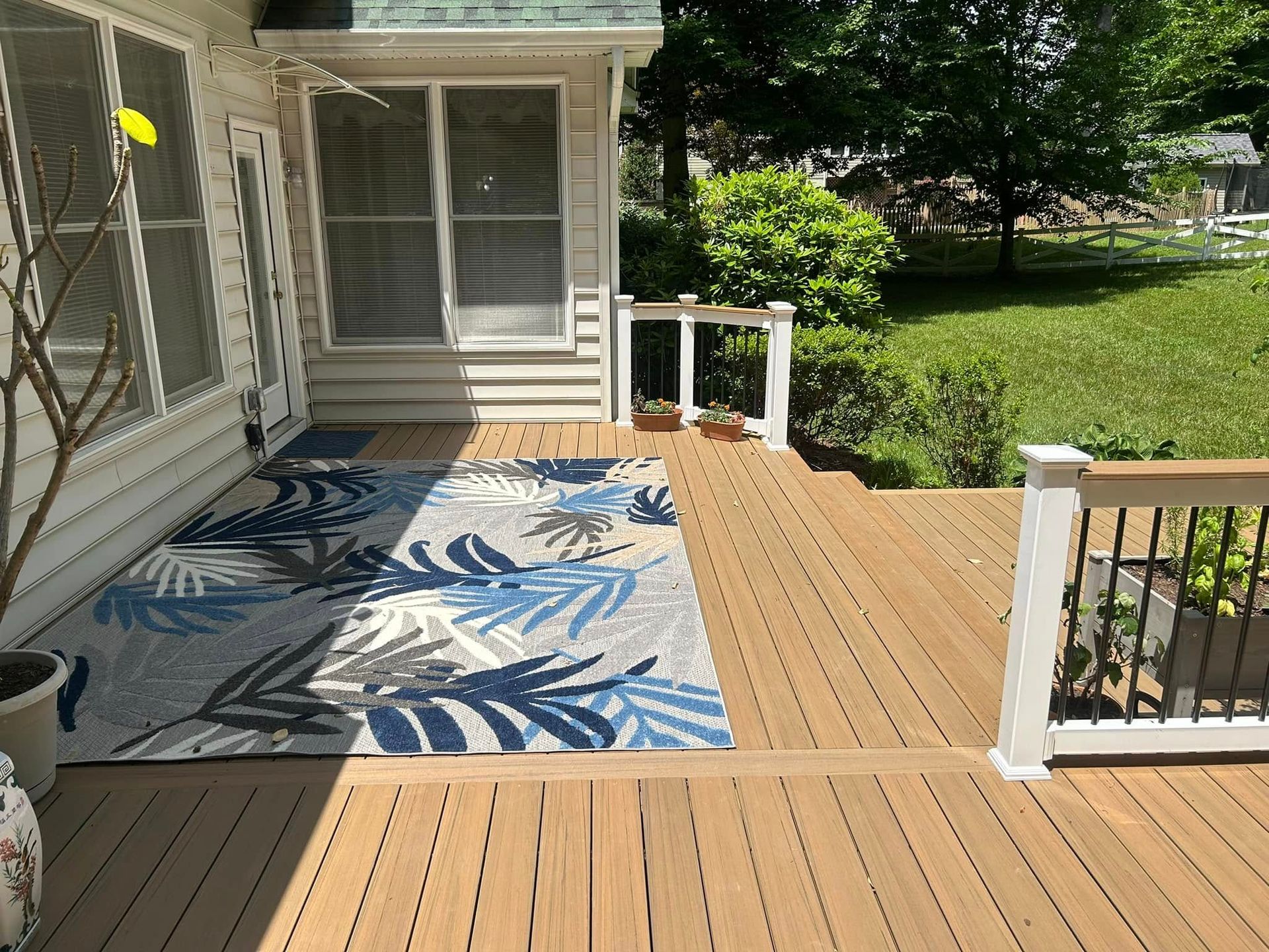 A wooden deck with a rug on it in front of a house.
