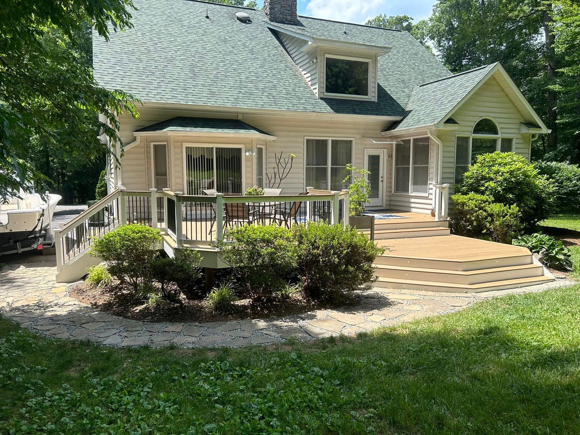A large white house with a green roof and a large deck.
