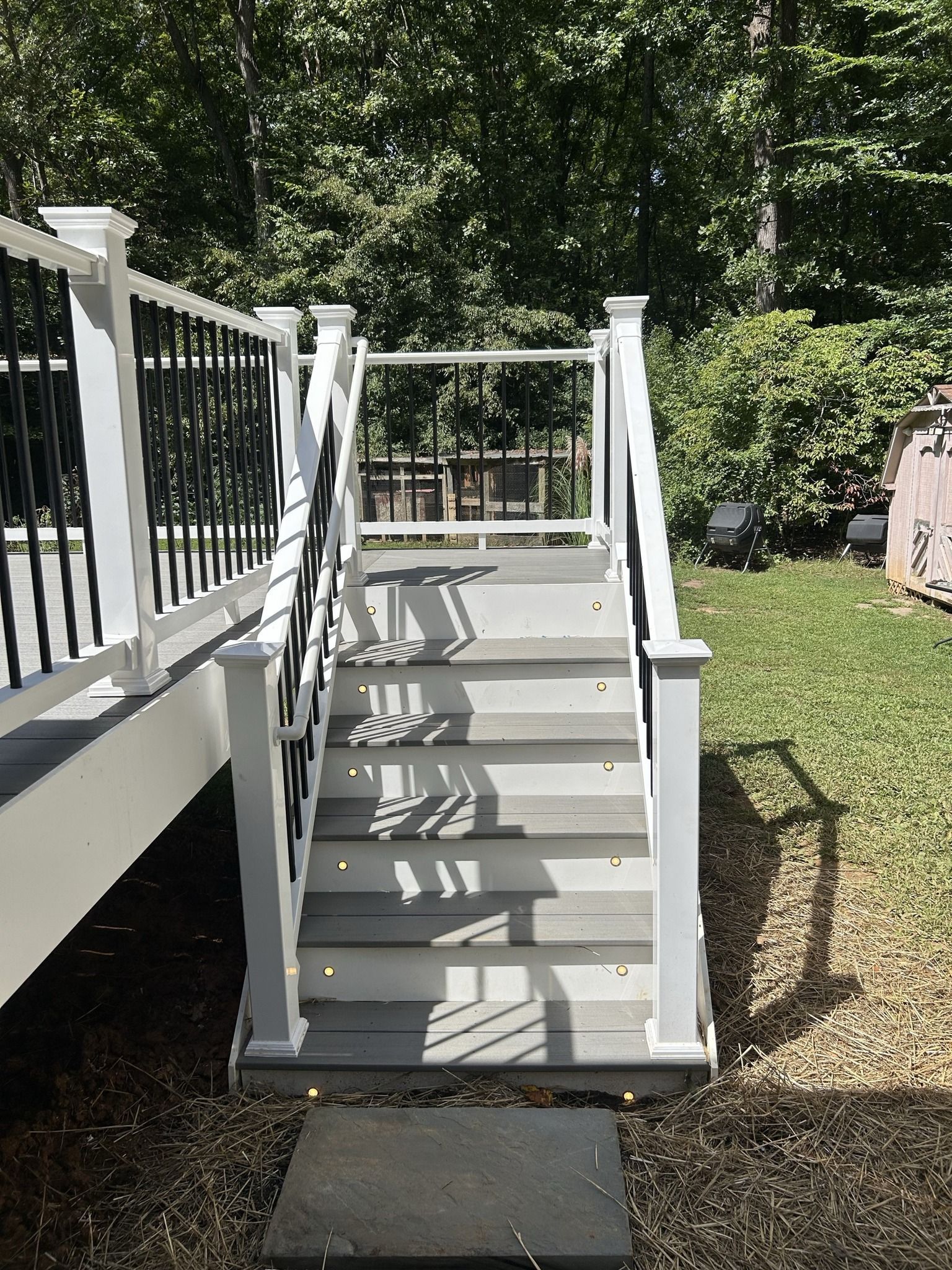 A set of stairs leading up to a deck with trees in the background.
