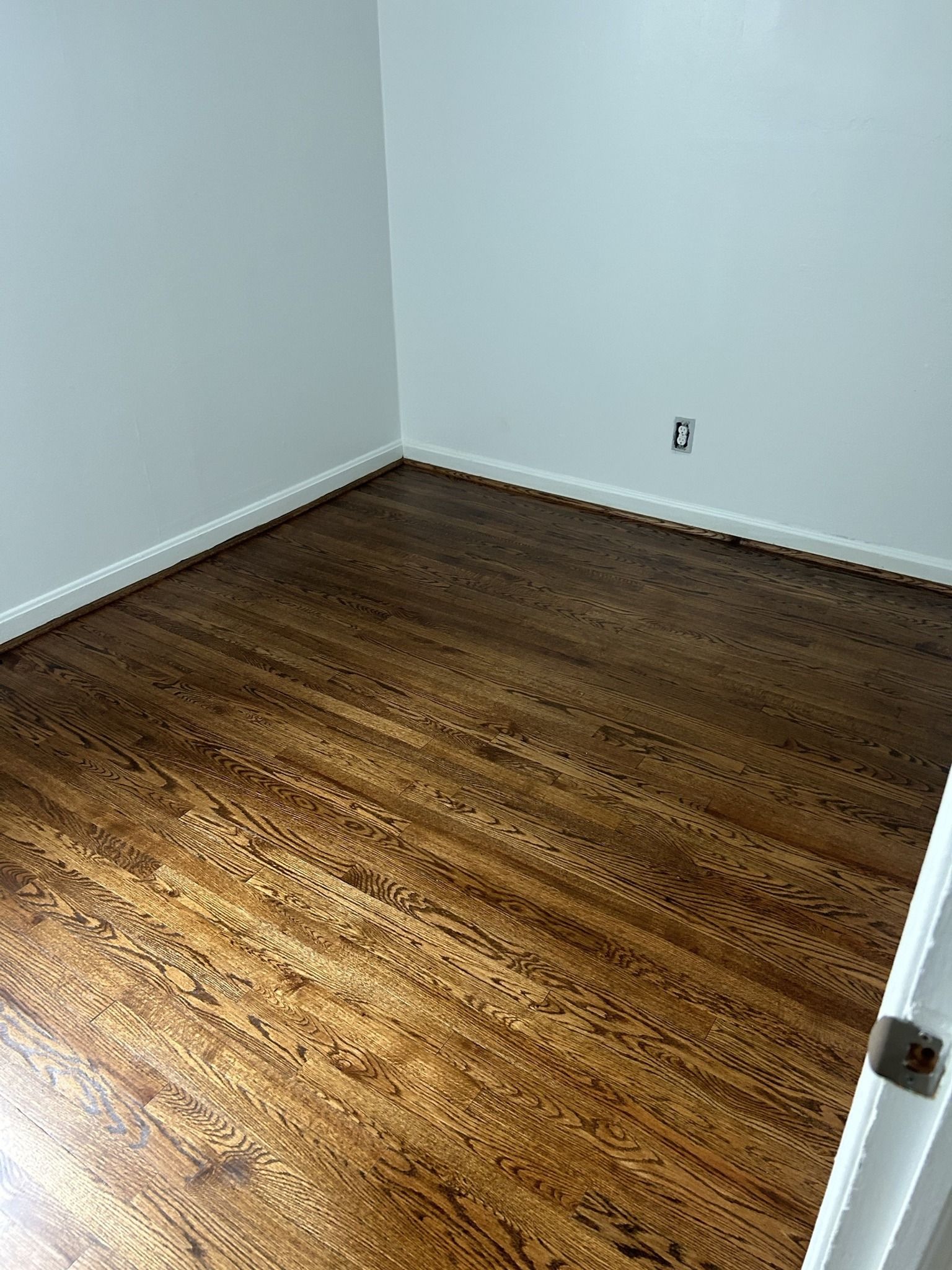 A bedroom with hardwood floors and white walls.