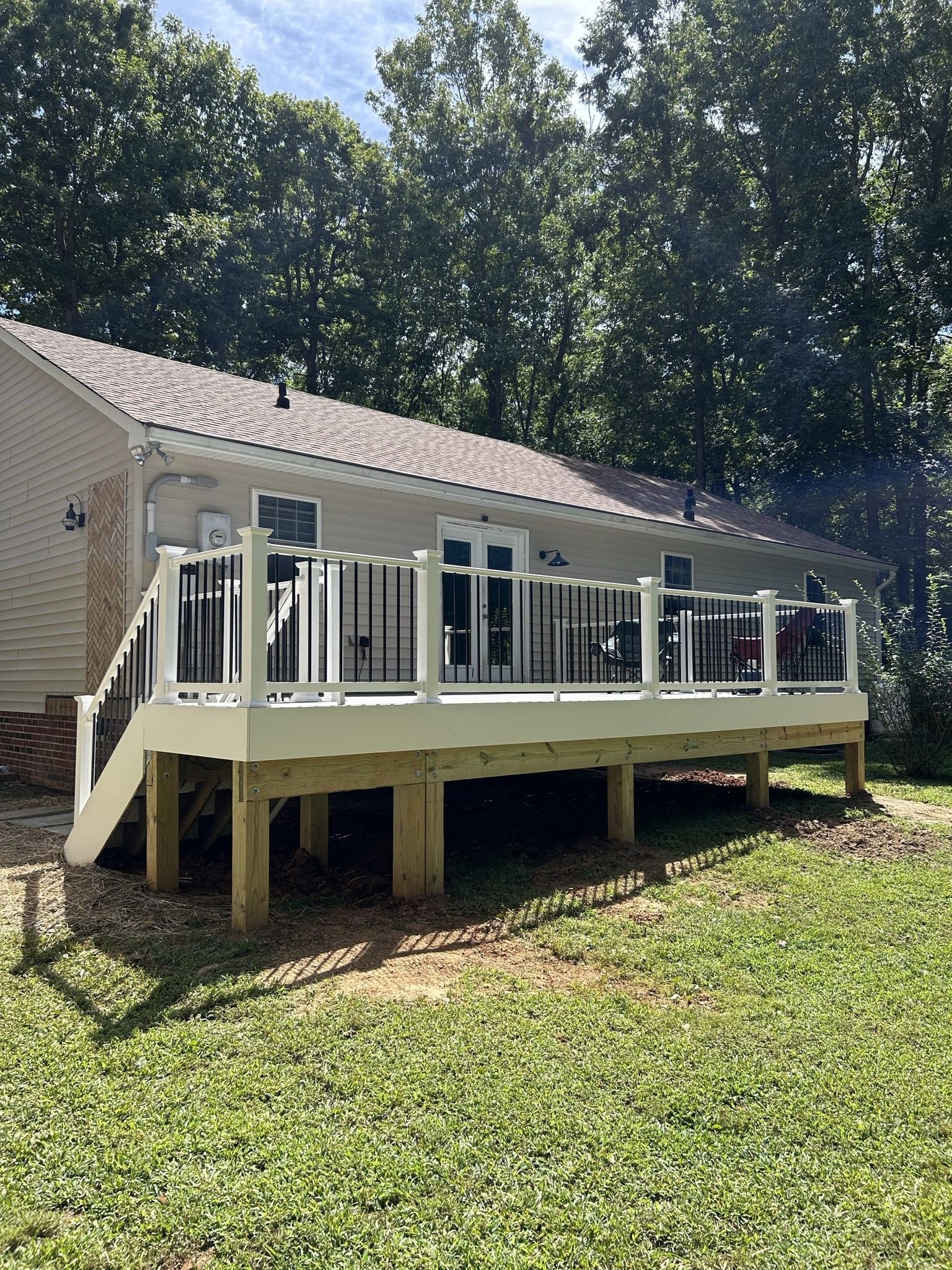A large white deck with stairs is in front of a house.