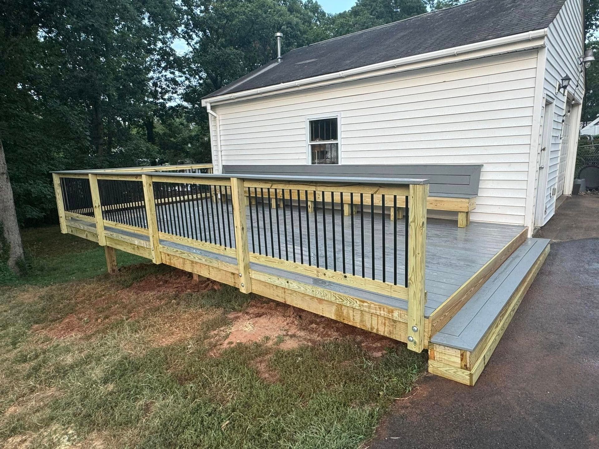 A wooden deck is sitting in front of a white house.