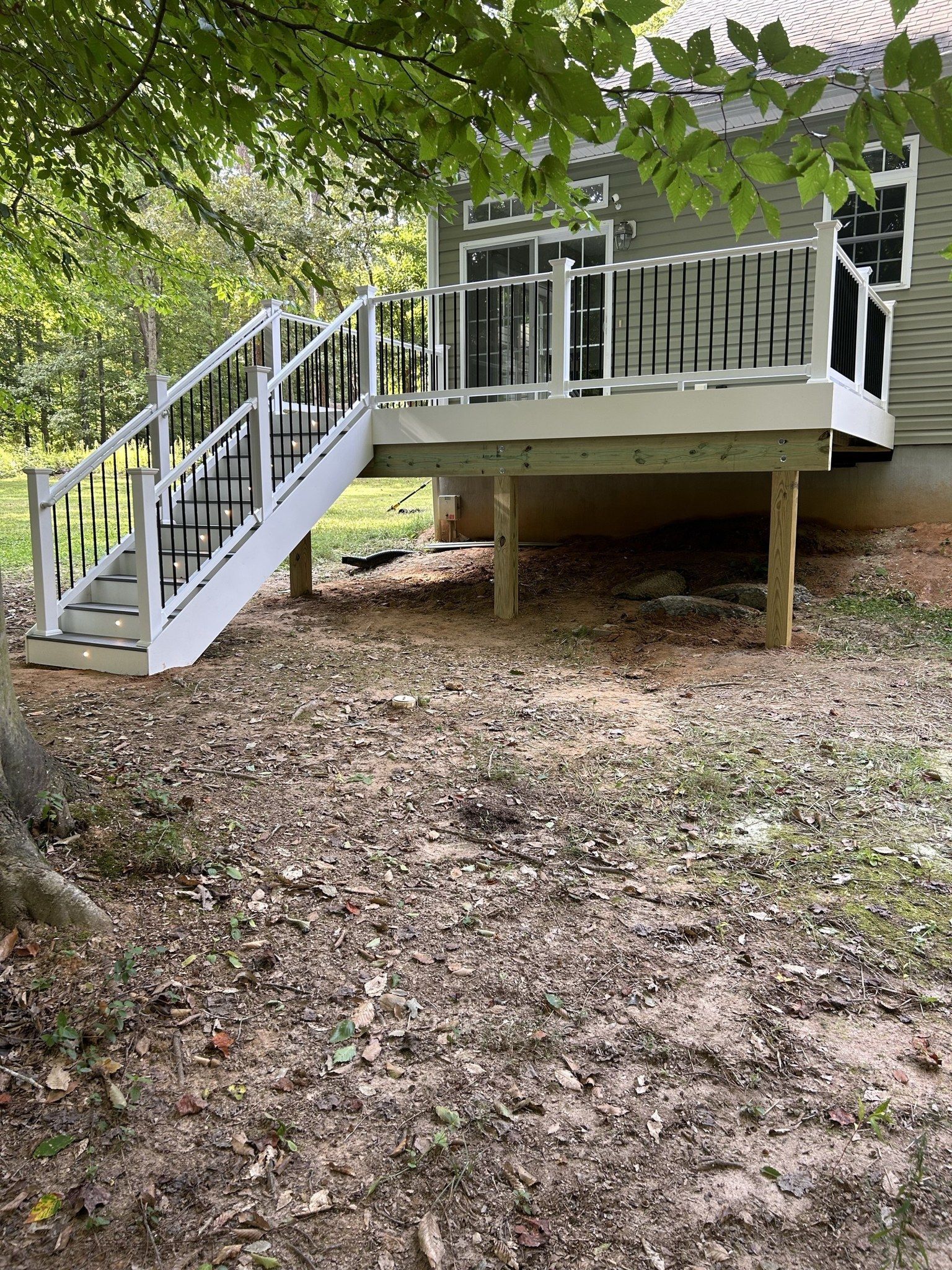 A deck with stairs leading up to it is in the backyard of a house.