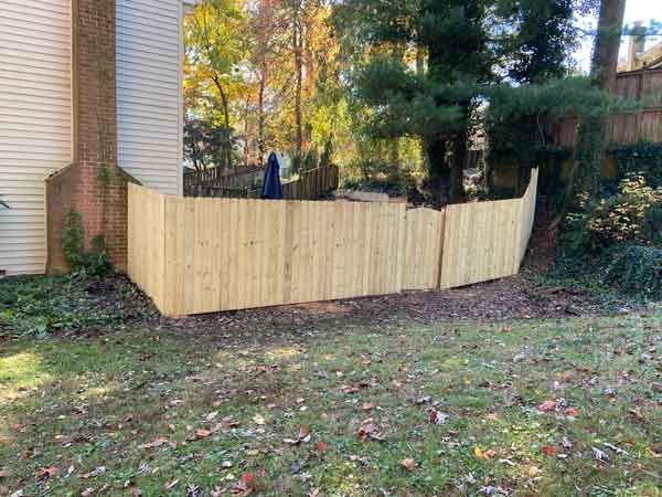 A wooden fence is in the backyard of a house.