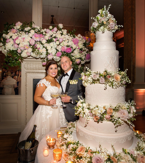 A bride and groom standing in front of a wedding cake