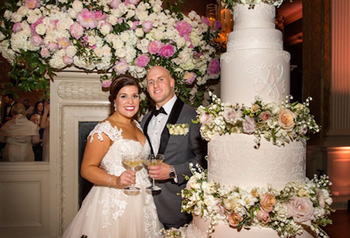 A bride and groom are standing in front of a large wedding cake.