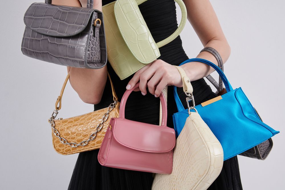 woman holding different statement bags and clutches