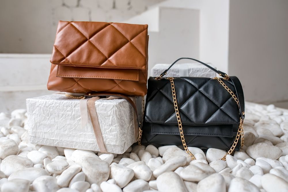 Three handbags are sitting on top of each other on a pile of rocks.