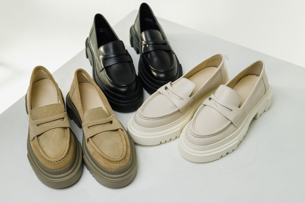 Three pairs of loafers are sitting on a table.