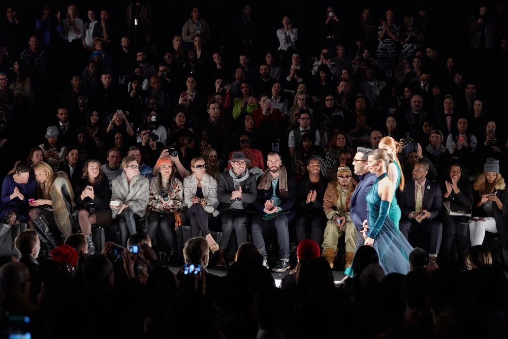 A woman in a blue dress is walking down the runway at a fashion show.