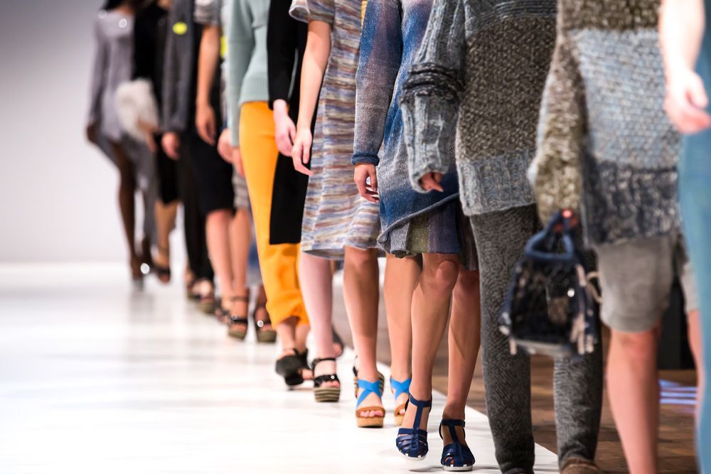 A row of models are walking down a runway at a fashion show.