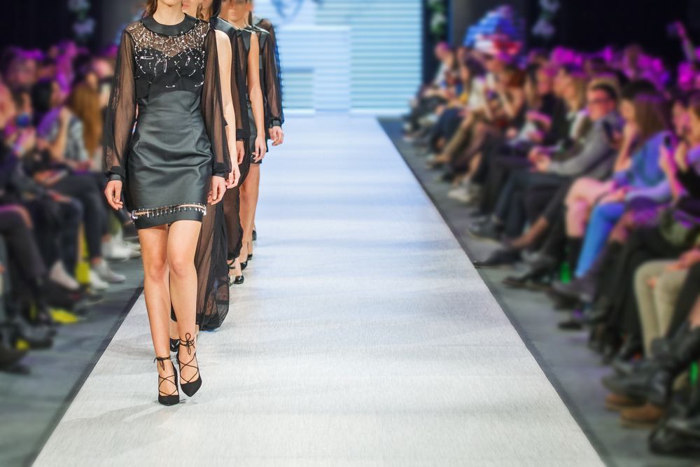A group of women are walking down a runway at a fashion show.