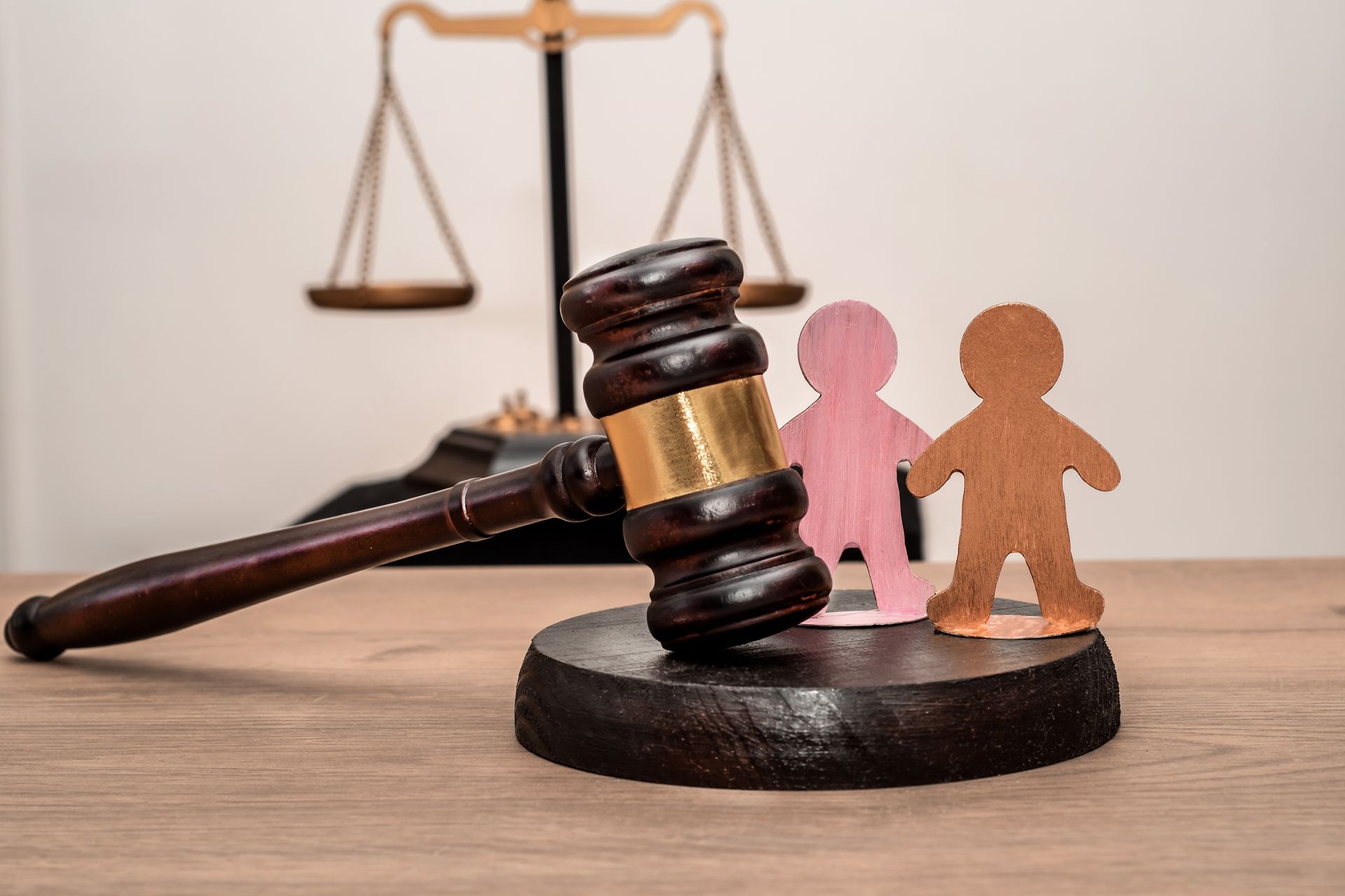 Gavel beside scales and two small paper figures on a desk, symbolizing legal equality
