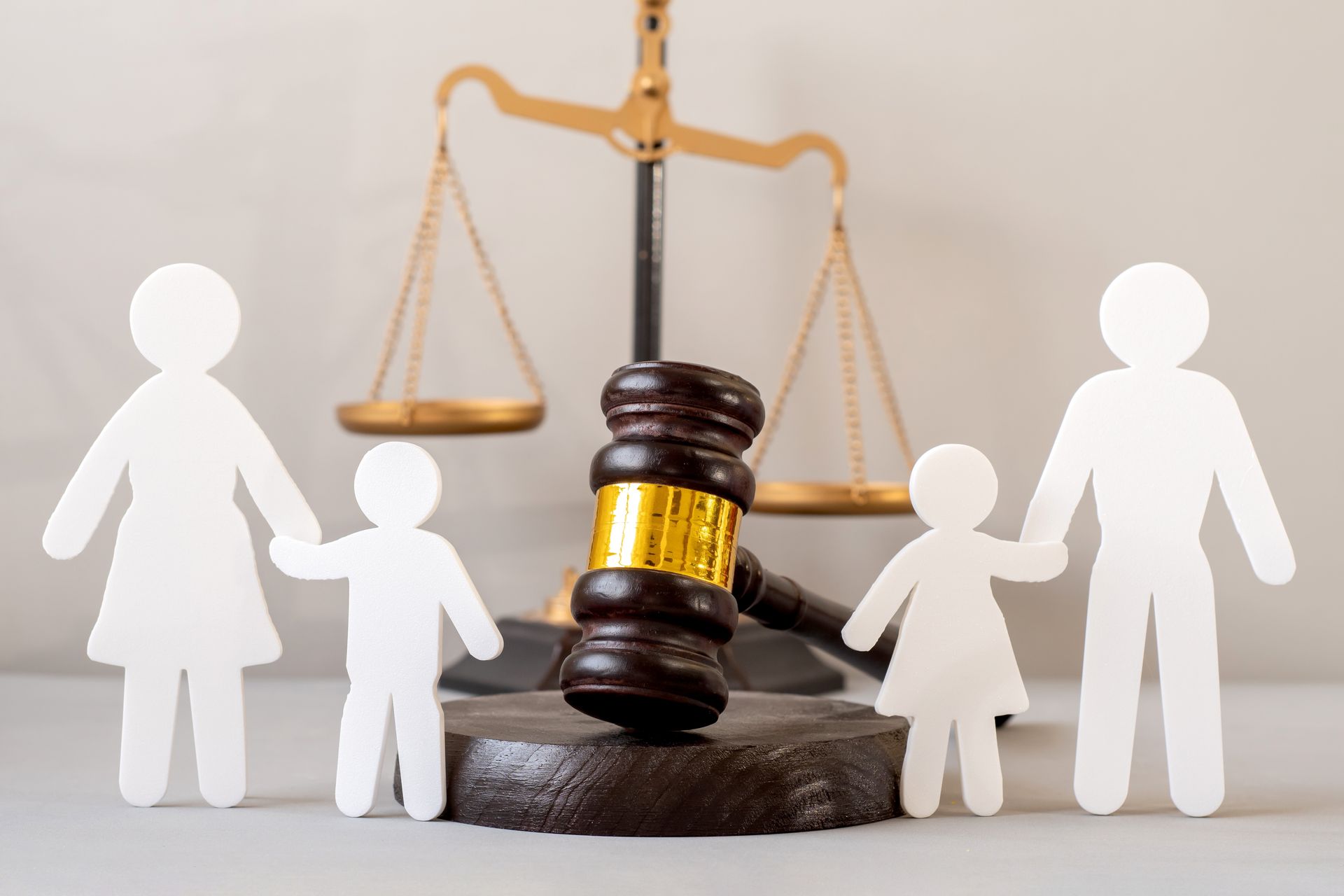 Scales of justice with a gavel and paper family cutouts in a legal concept scene