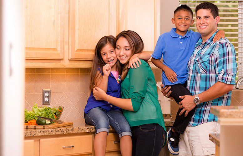 Family of four hugging in kitchen