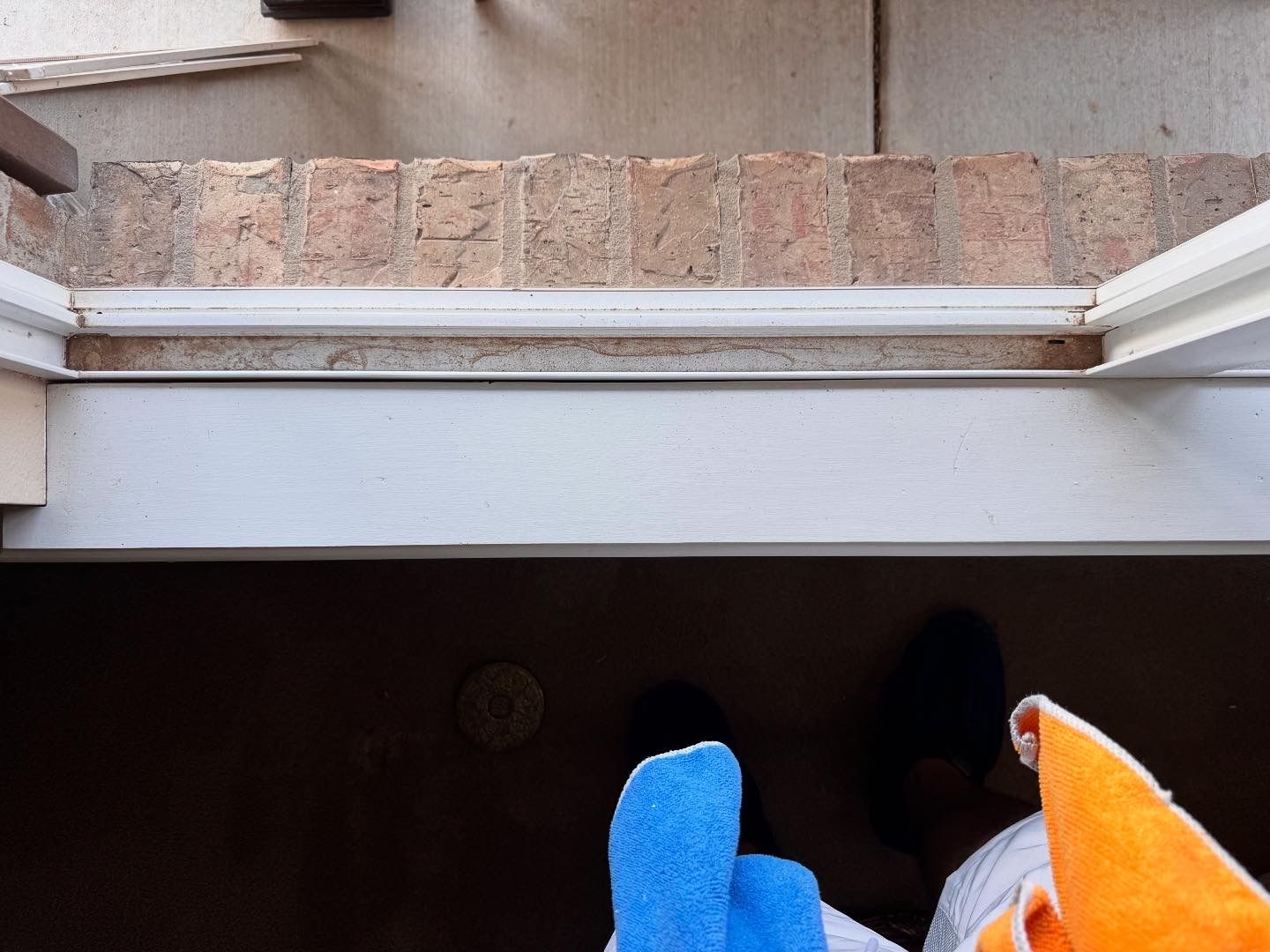 Looking down from a window frame; blue and orange socks visible.