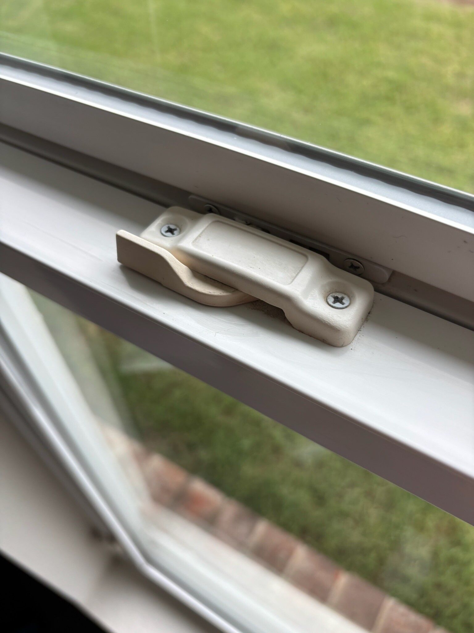 White window lock latch on a white window frame, outdoors.