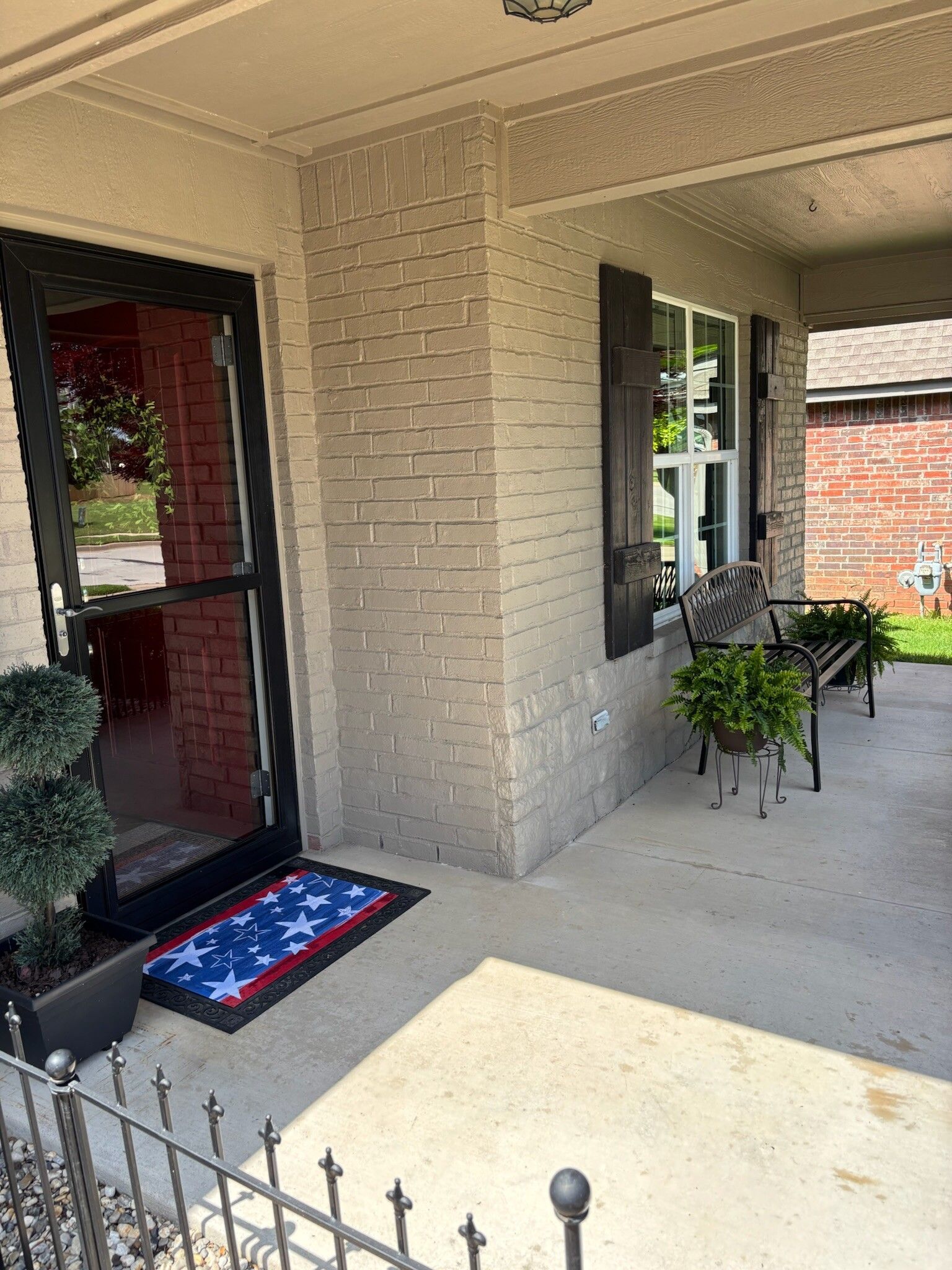 Exterior of a home with a porch featuring a welcome mat, potted plants, and seating.