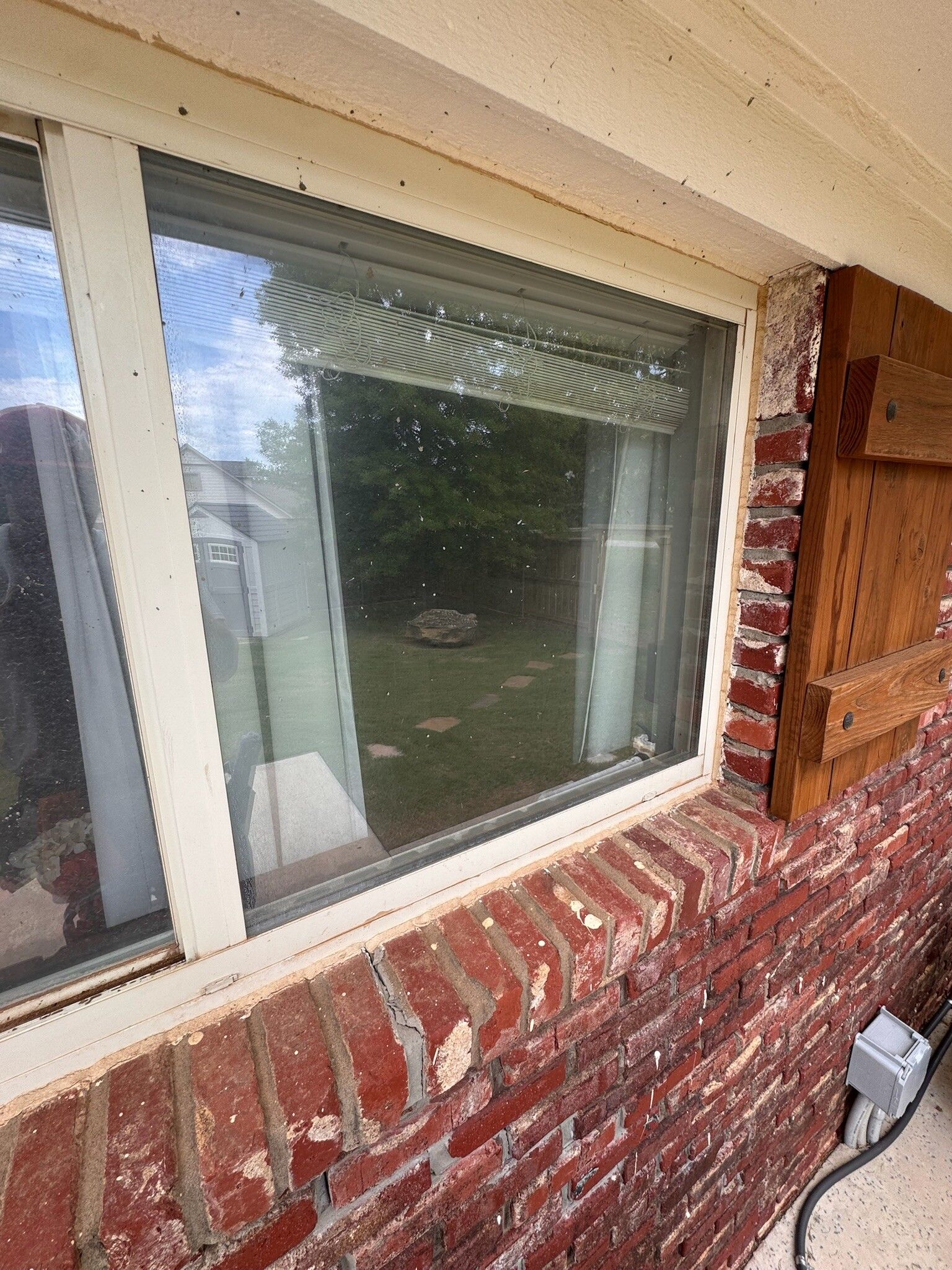 Window in brick wall with white trim and a partially closed shade.