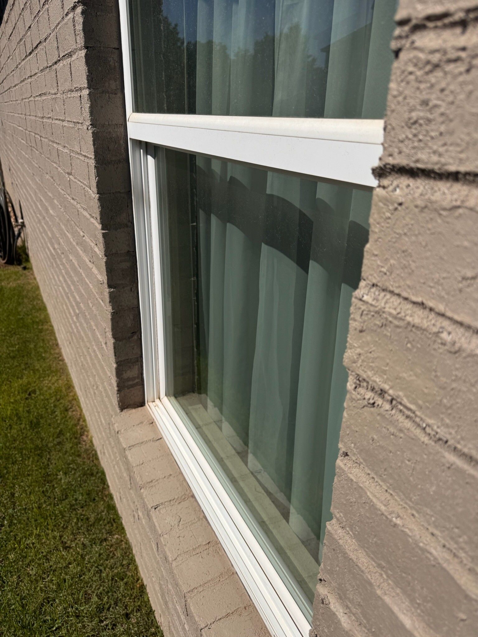 Exterior view of a window set in a brick wall with vertical blinds.