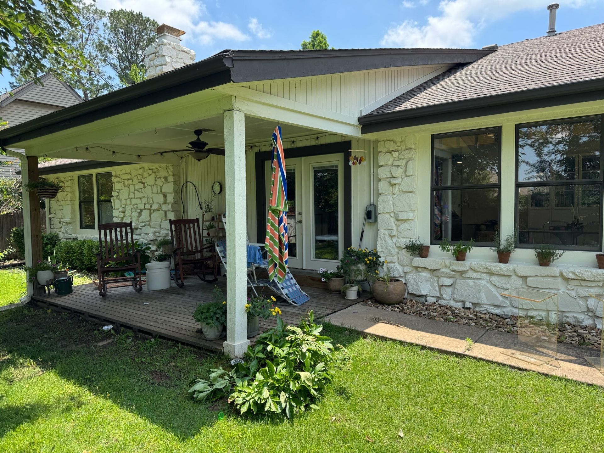 House with stone exterior and covered porch; lawn in foreground, blue sky.