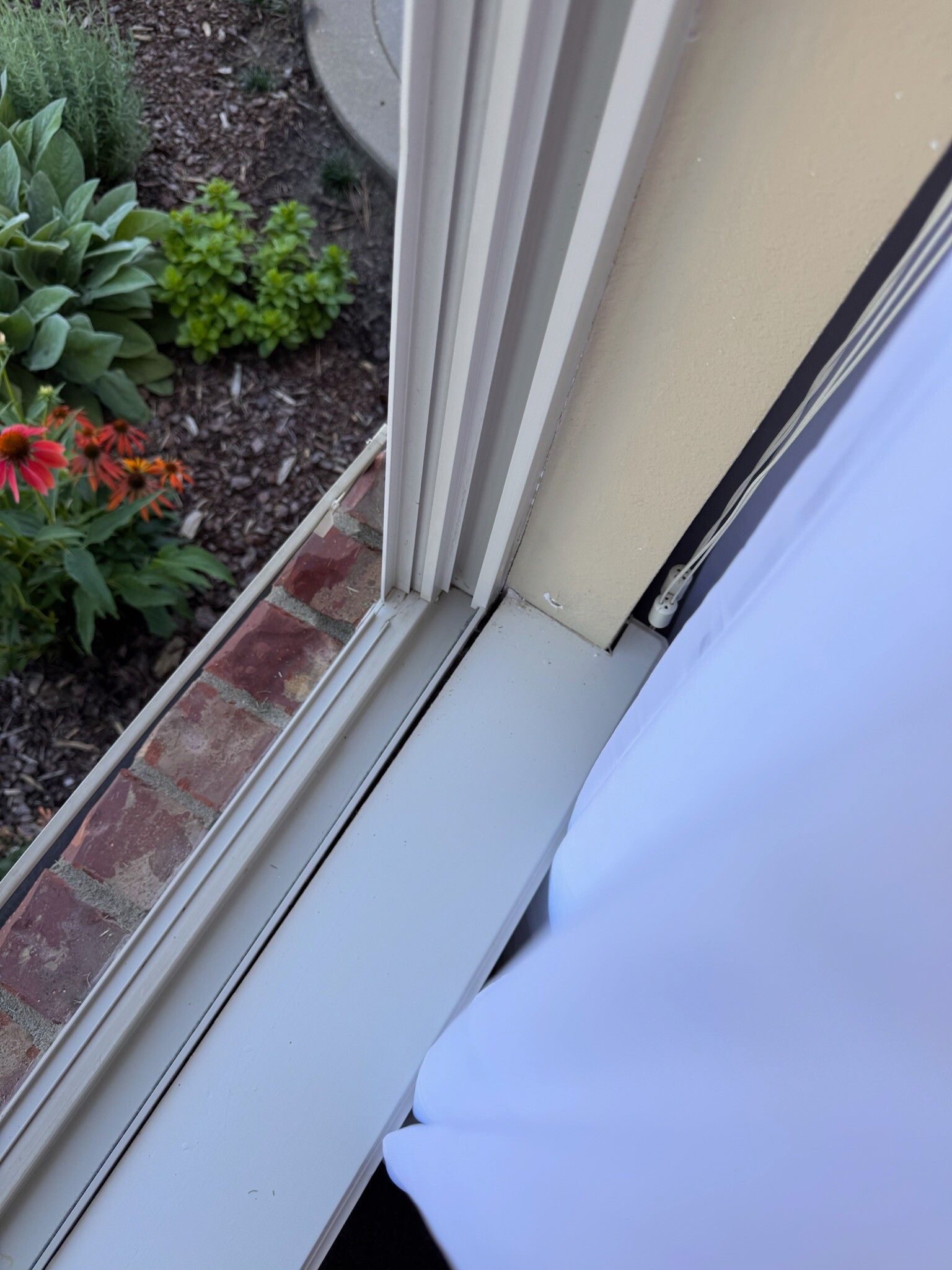 Window frame with brick exterior and white curtain.