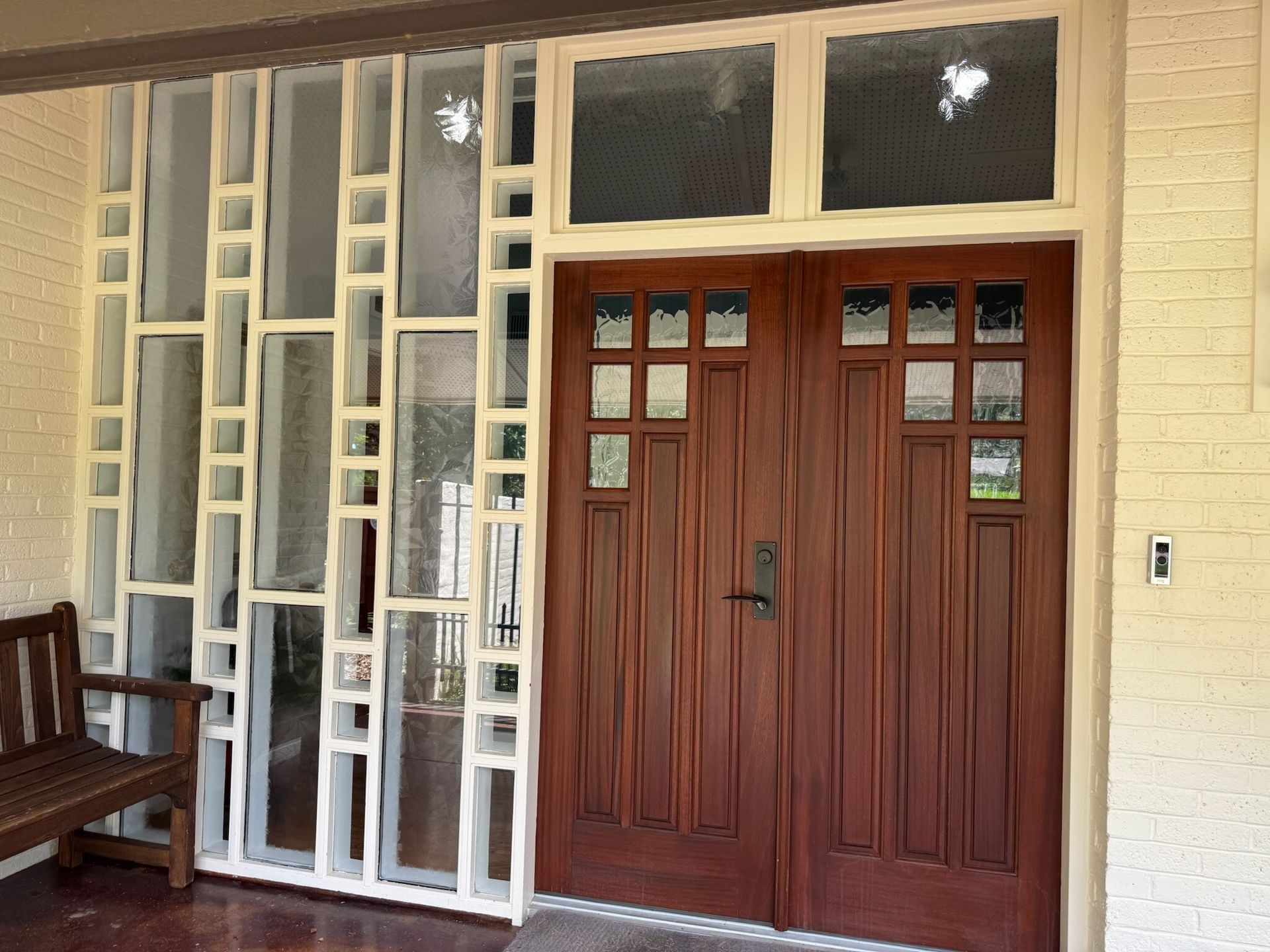 White geometric screen and wooden double doors on a building's entrance.