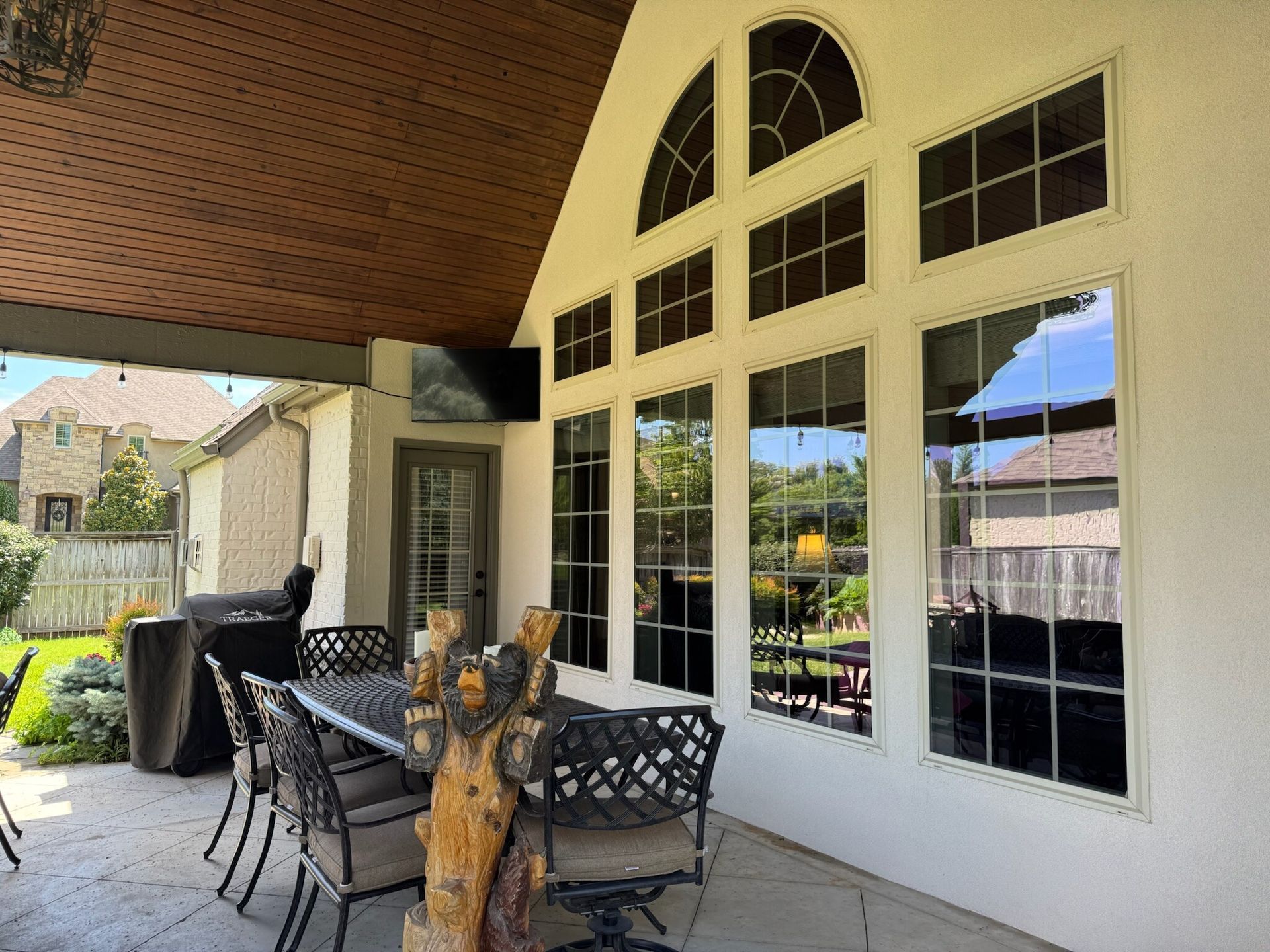 Patio with dining table, outdoor windows, and a partial view of a backyard.