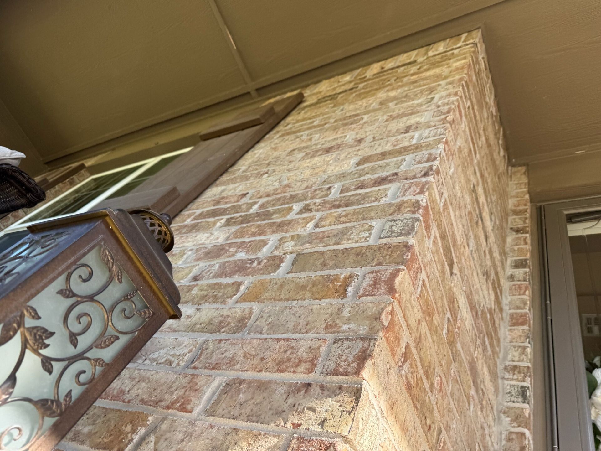 Brick wall of a building corner with a brown light fixture and a window.