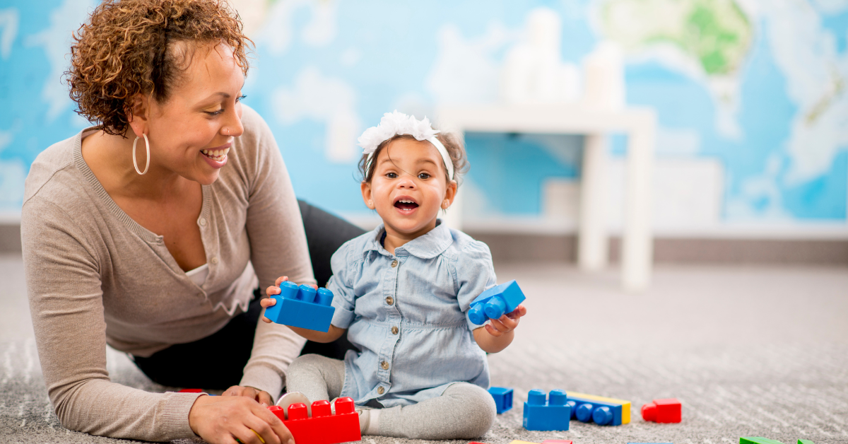 A woman and a little girl are playing with lego blocks on the floor.