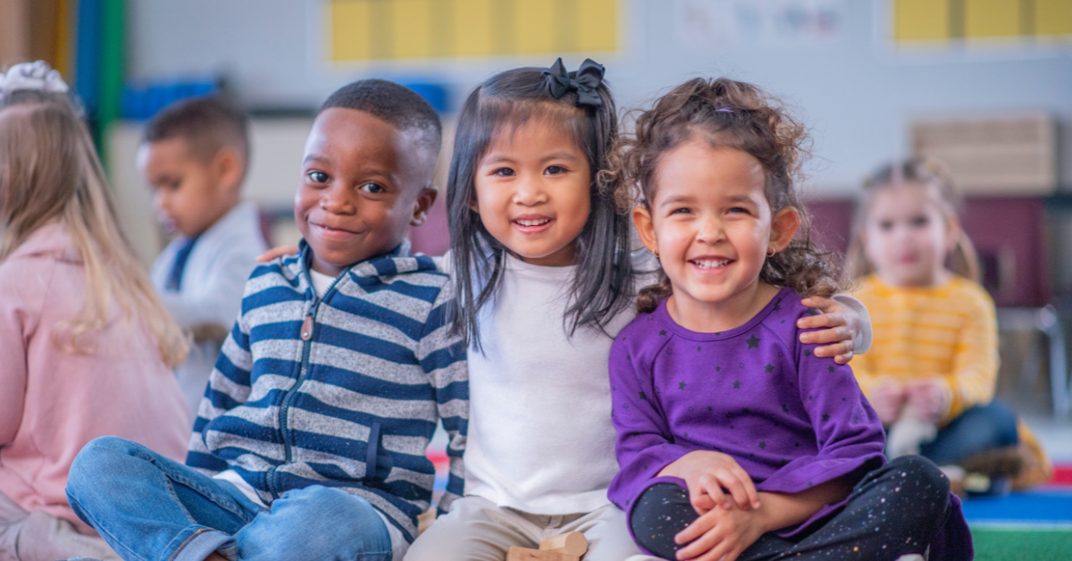 A group of children are sitting on the floor in a classroom.