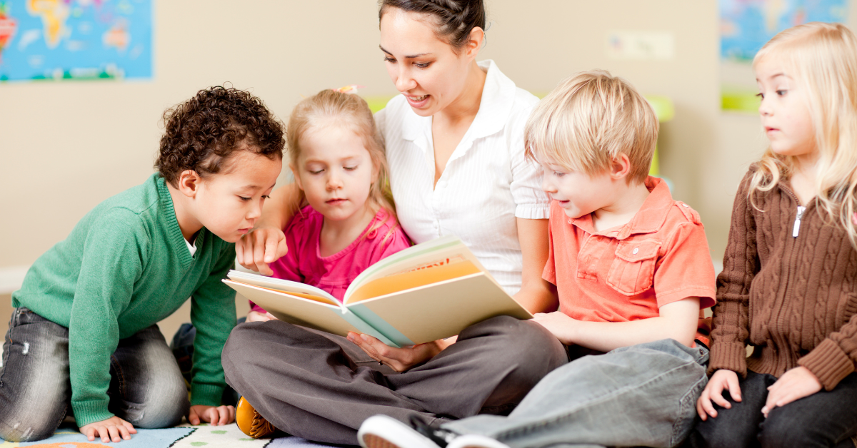 A woman is reading a book to a group of children.