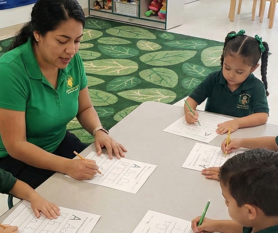 Teacher assisting children at a round table; children writing and playing with toys in a classroom.