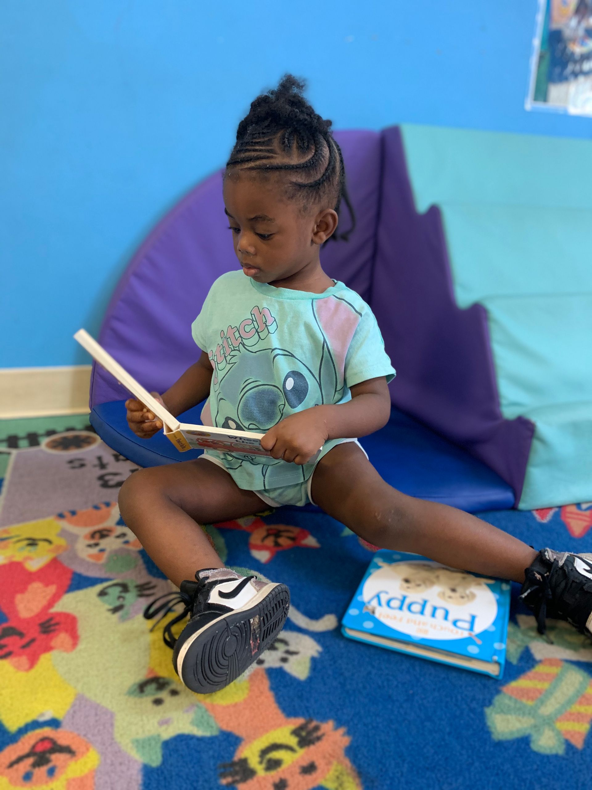 A little girl is sitting on the floor reading a book called puppy