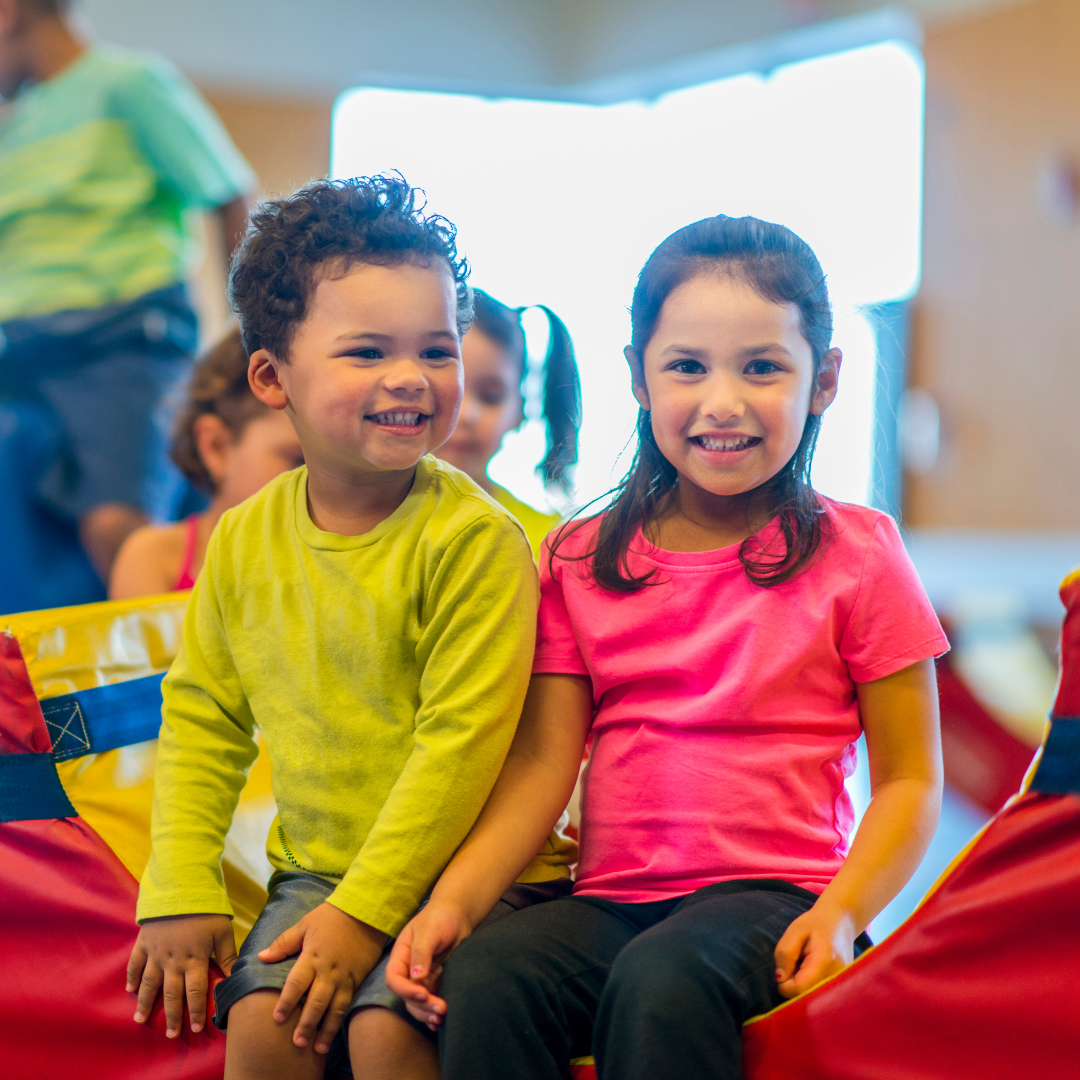 A boy and a girl are sitting next to each other and smiling.