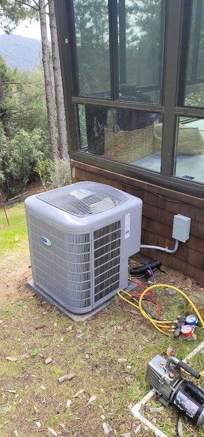 A large air conditioner is sitting on top of a lush green field next to a window.