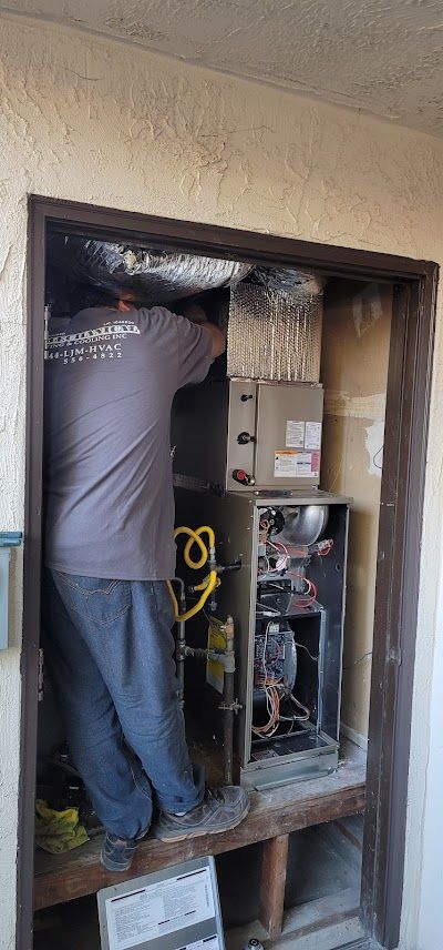 A man is working on an air conditioner in a doorway.