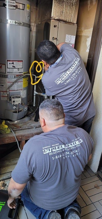 Two men are working on a water heater in a room.