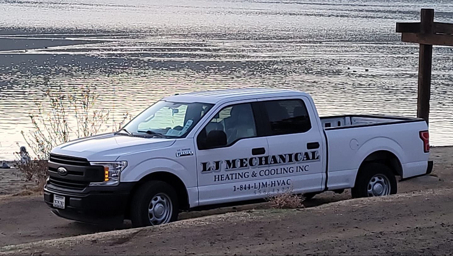 A white pickup truck is parked next to a body of water.
