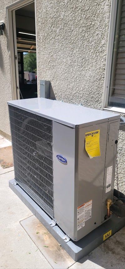 A large air conditioner is sitting outside of a building next to a window.