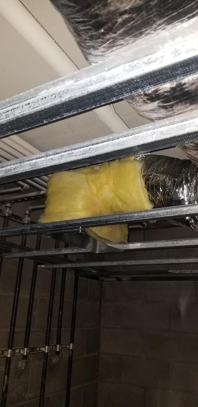 A piece of insulation is hanging from the ceiling of a building.